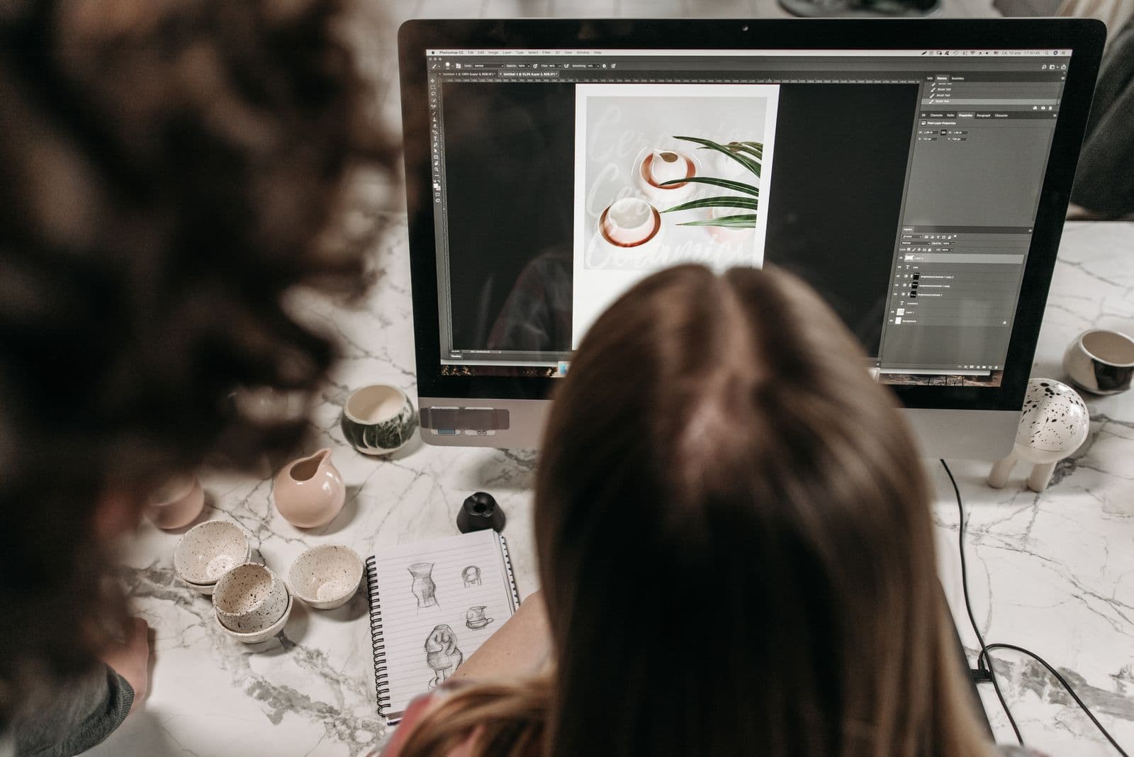 Two people collaborating while editing a photograph on a desktop computer
